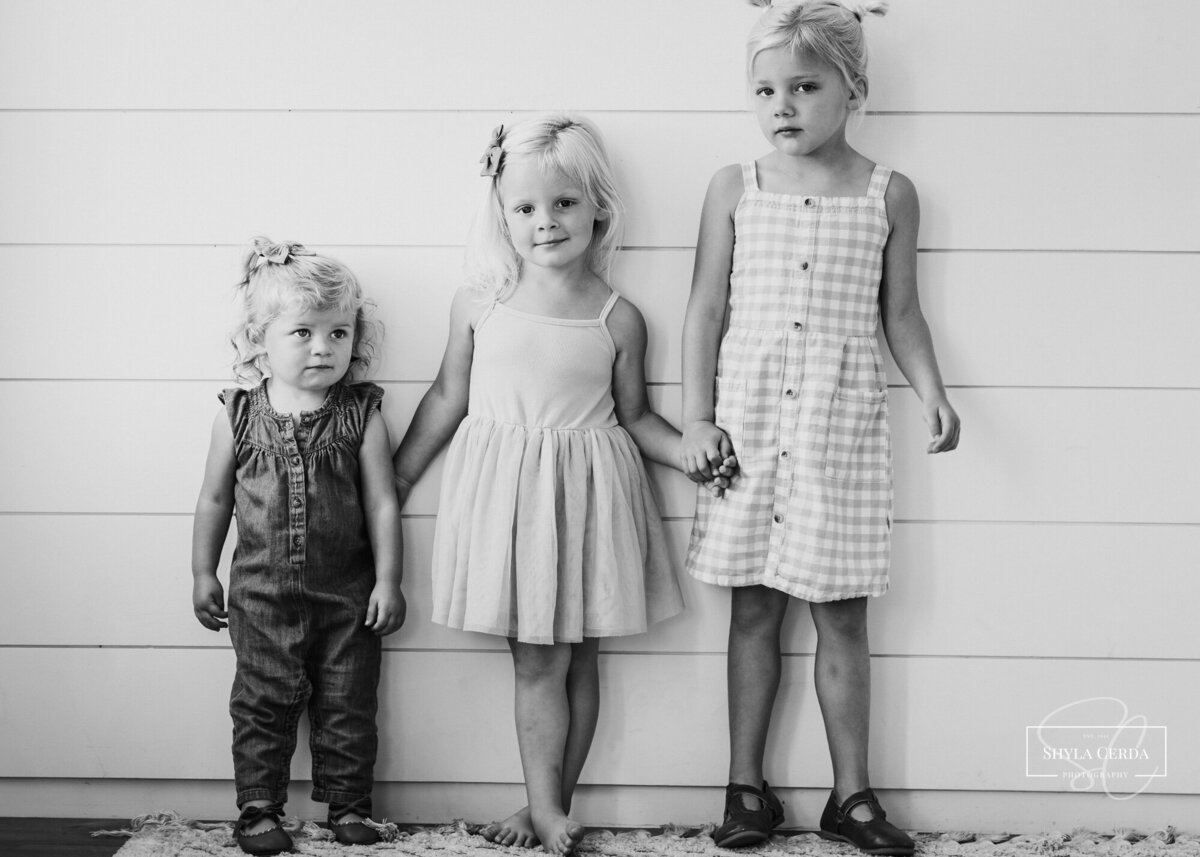 Three siblings holding hands during studio session
