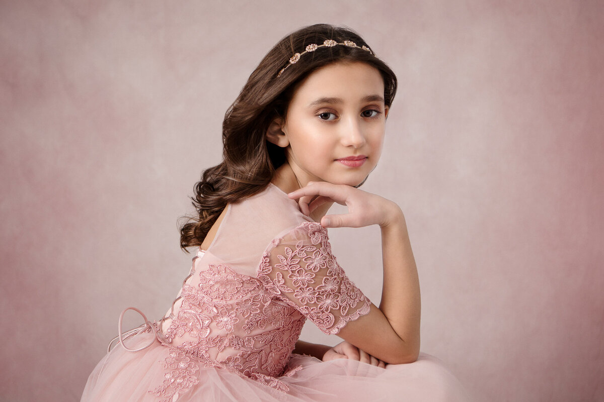 Girl in pink dress posing in front of pink backdrop