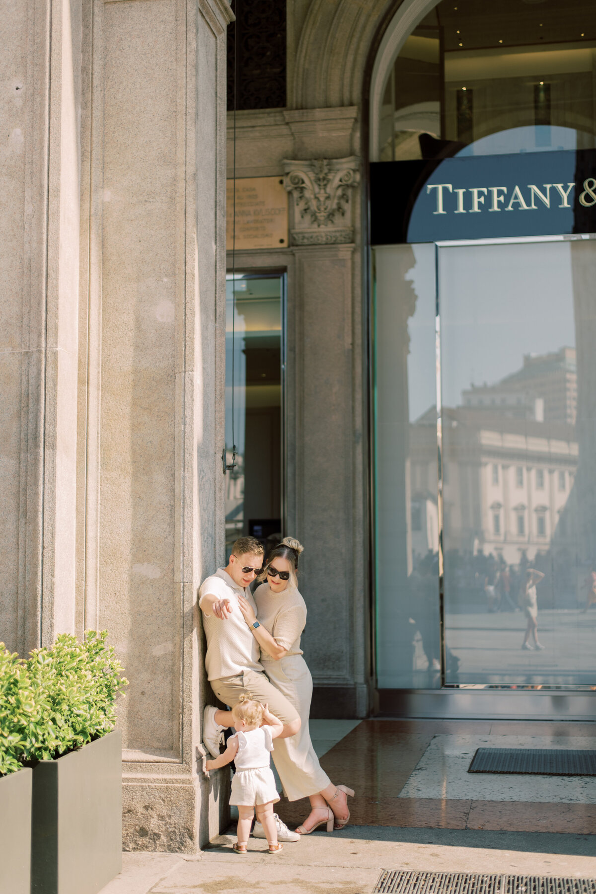 Parents and daughter sharing a quiet moment outside a Milan boutique during their family photo session