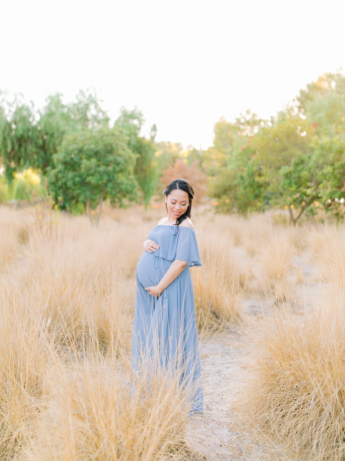 maternity portrait wearing blue flowy dress at yellow brown grass field in yorba linda