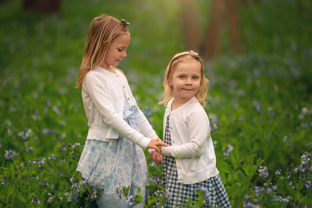 Two young sisters hold hands in a meadow at Retzer Nature Center in Waukesha, WI.