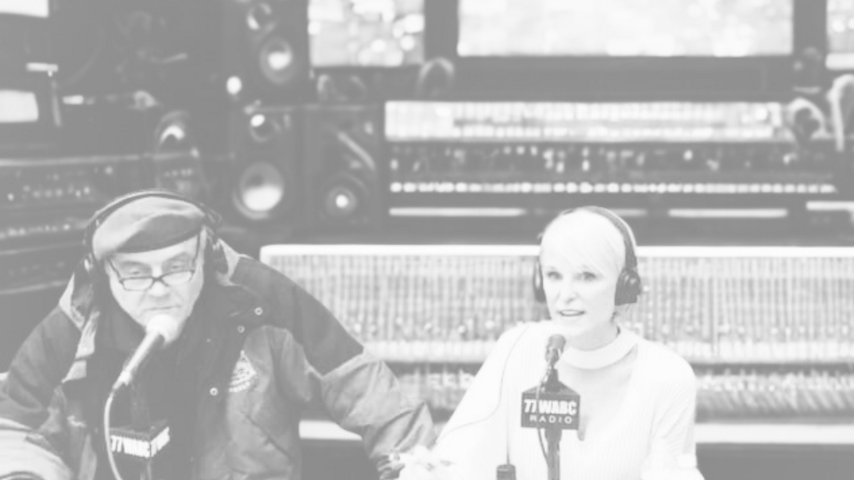 Female and male hosts sitting on a radio set hosting a talk show. 
