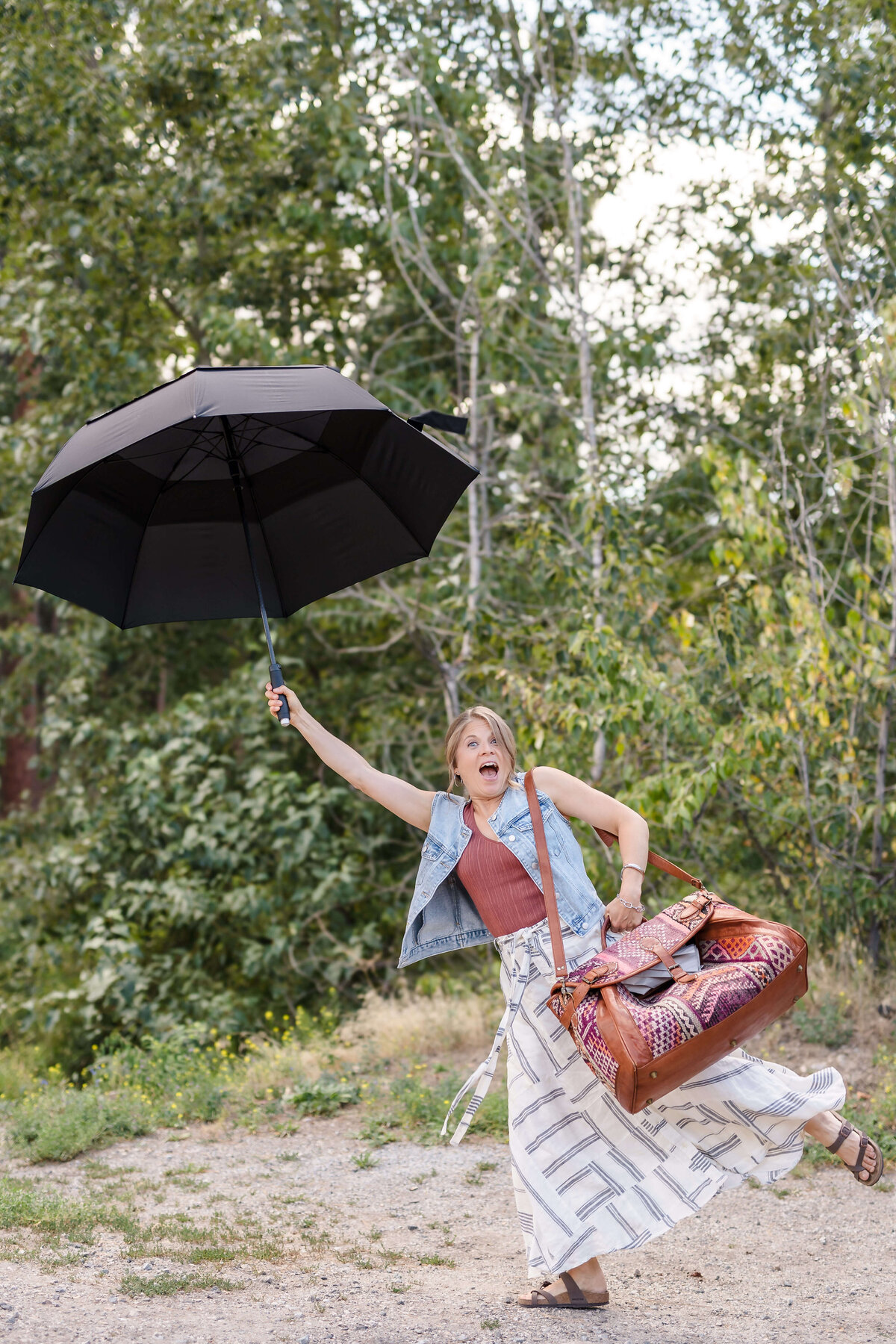 woman holding black umbrella and mary poppins style bag for creative photoshoot