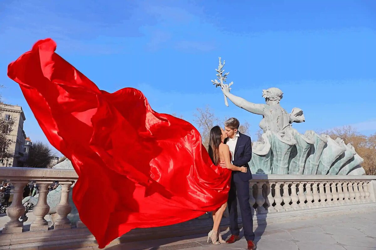 a couple having a photoshoot in paris with a red flying dress