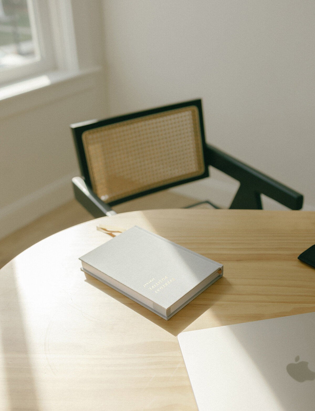 wood desk with gray linen journal, gold lettering, black chair