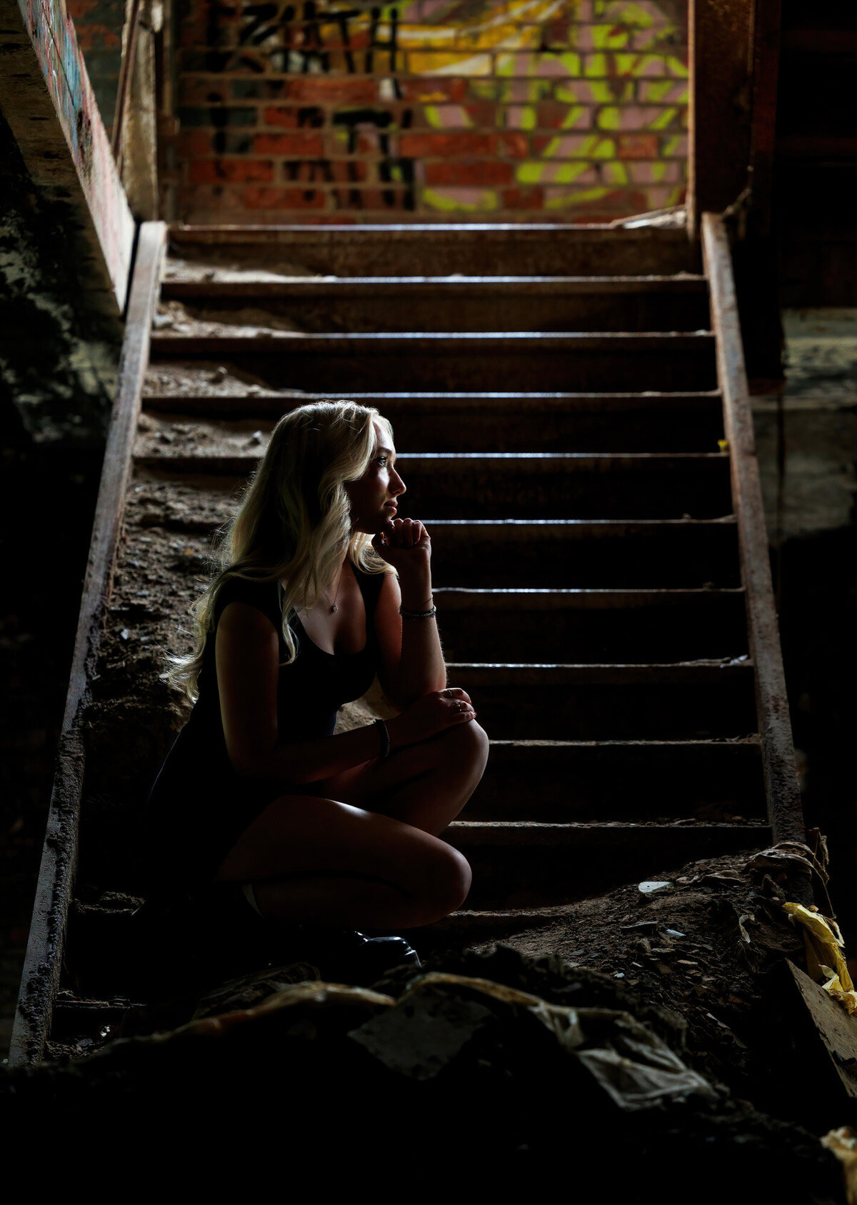 Maria sits on an old staircase in the abandoned building.