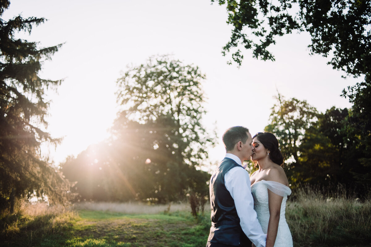 Newly married couple sharing a kiss in a woodland area at sunset taken by London Wedding Photographer Liberty Pearl
