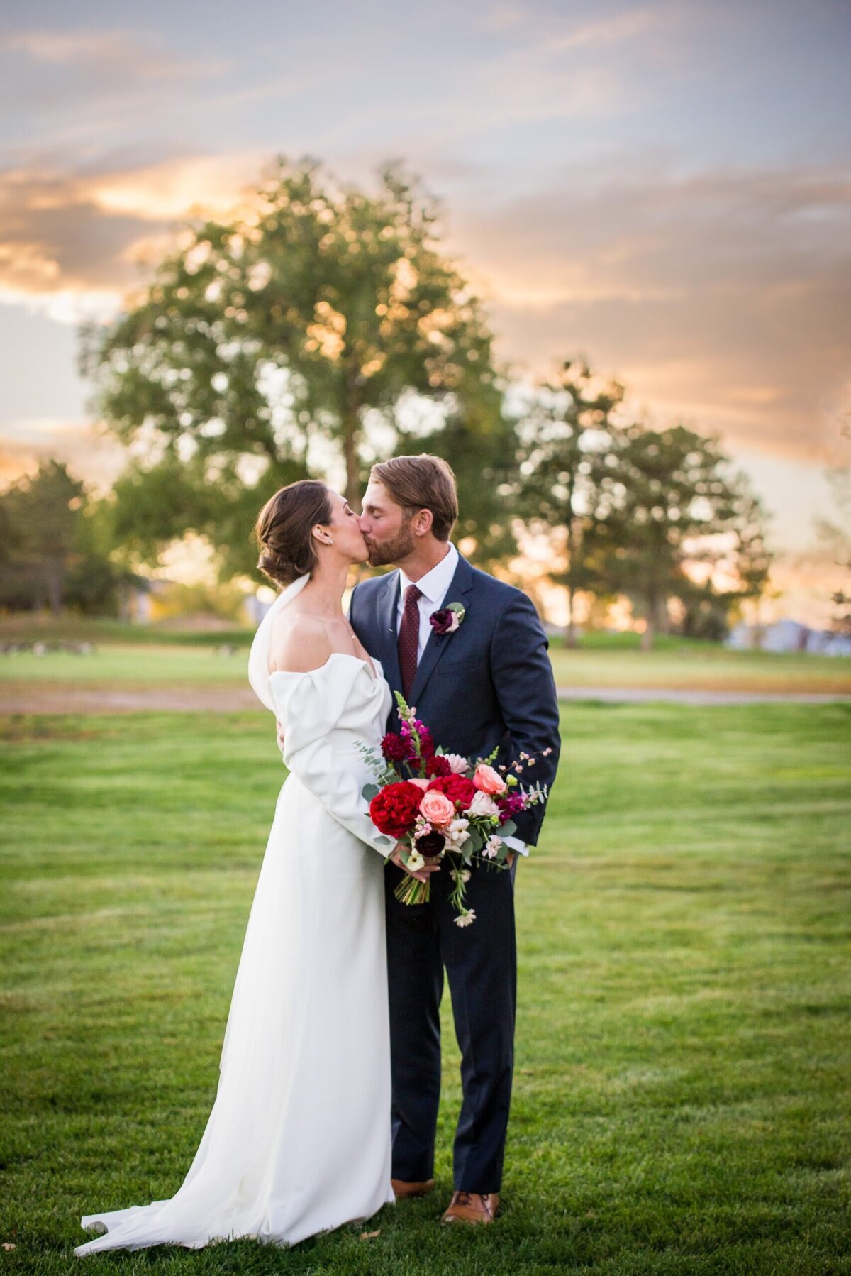 A bride and groom share a kiss at golden hour at The Barn at Raccoon Creek in Denver, Colorado.