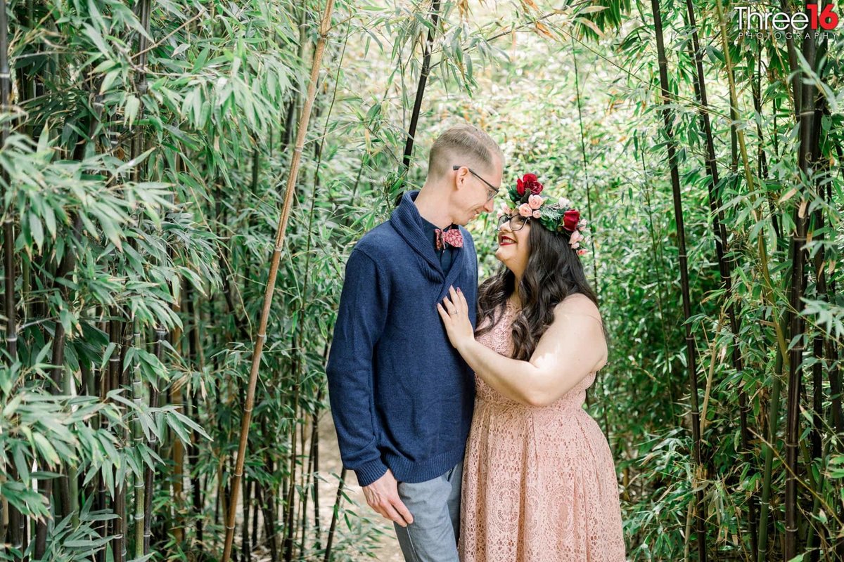 Engaged couple gaze at each other along the Fullerton Arboretum trail of plants