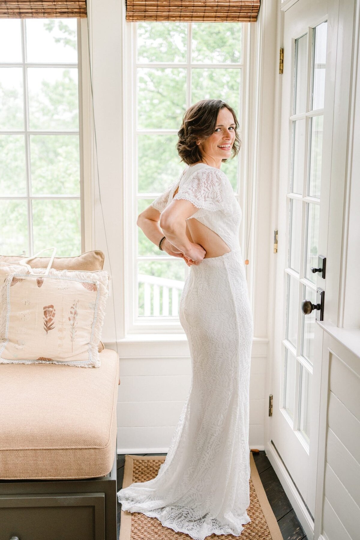 Bride zips up dress while getting ready at Waterperry Farm wedding