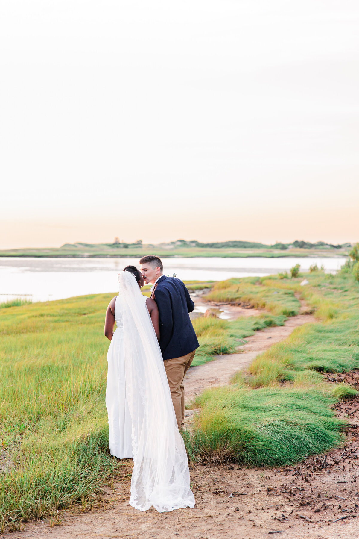 Bride and groom kissing and walking away from the camera at Gray's Beach representing the best Cape Cod wedding photographer
