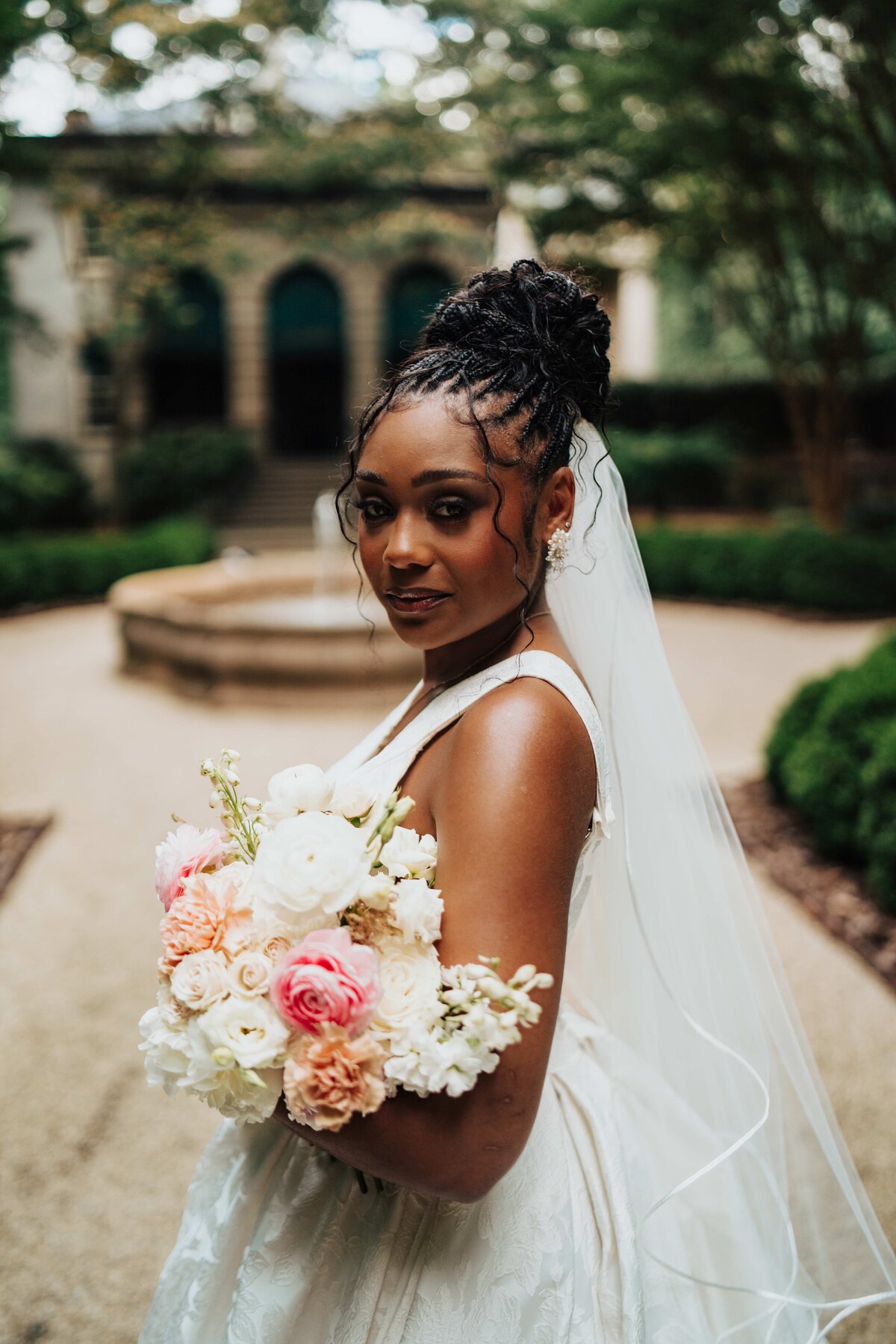 Beautiful black bride holds white and muted pink flowers in a bouquet made by Scottsdale wedding florist