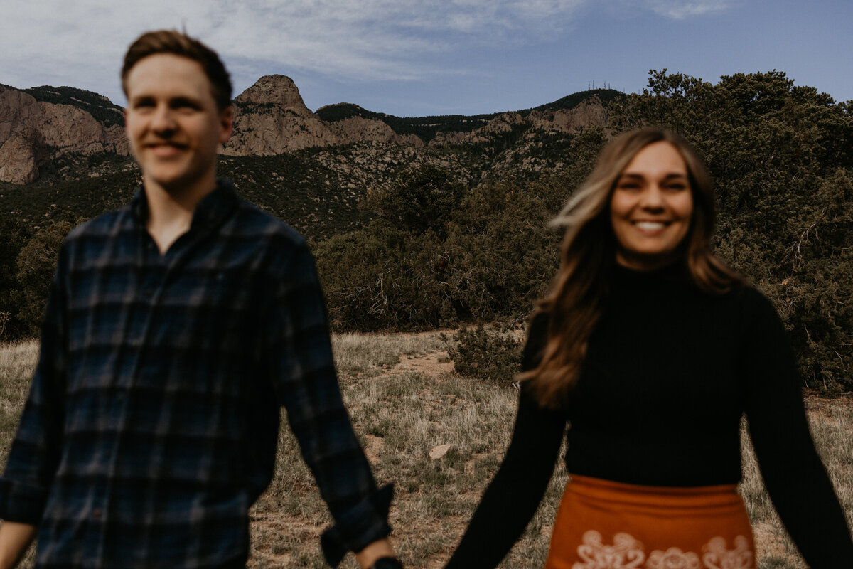 engaged couple running along the foothills of the Sandia Mountains in Albuquerque