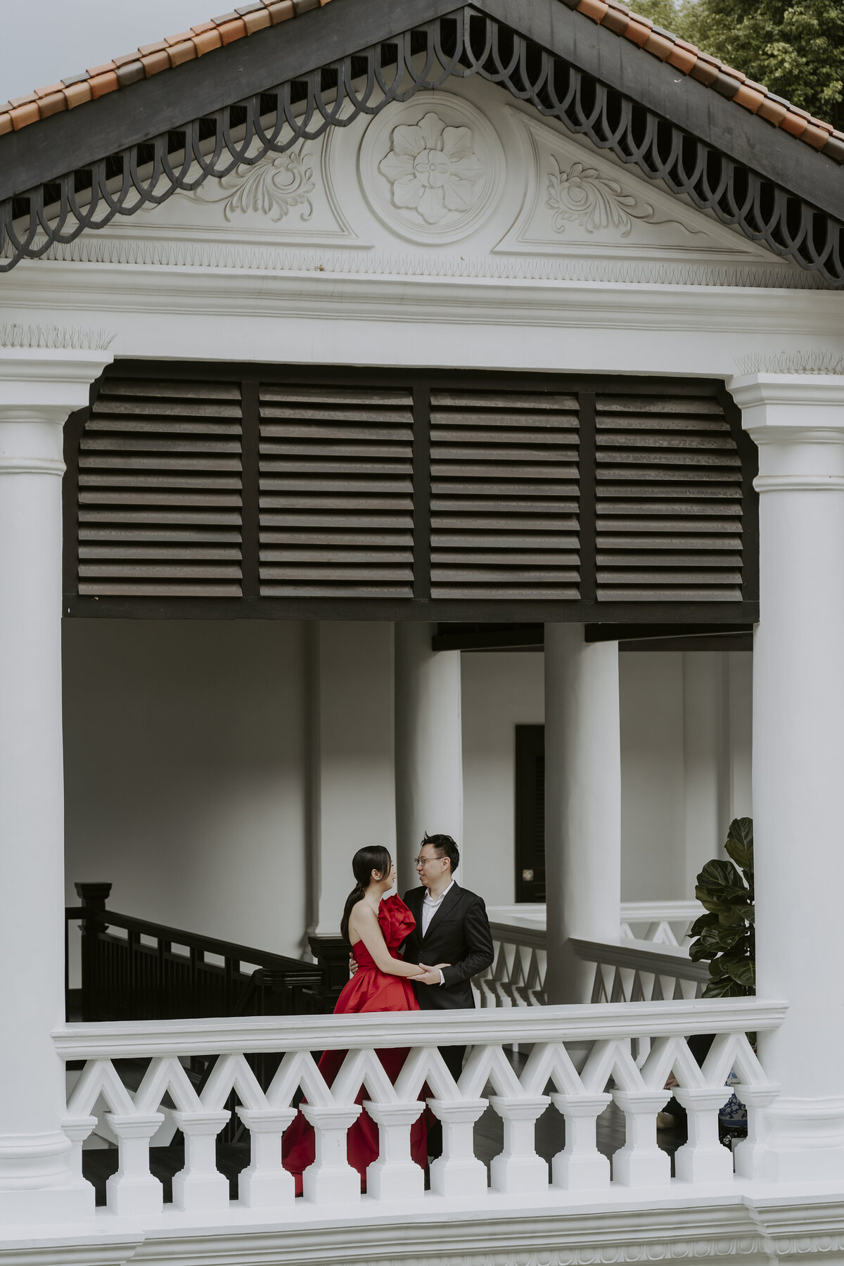 woman in red cheongsam  dress and a man in a black suit hold each other