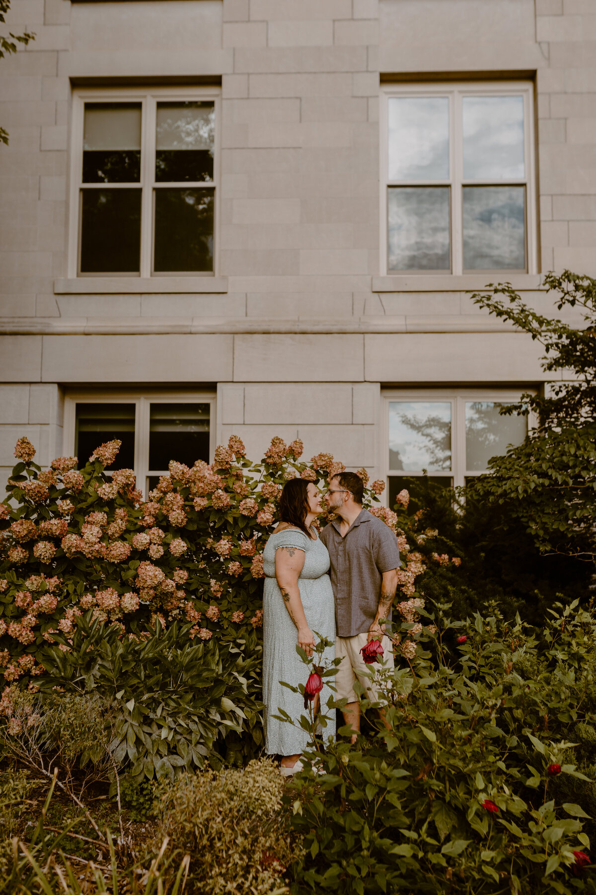 Engagement-portrait-with-cuddling-couple-around-flowers-iowa-state-university-ames-iowa-storyteller-collective-photo-co
