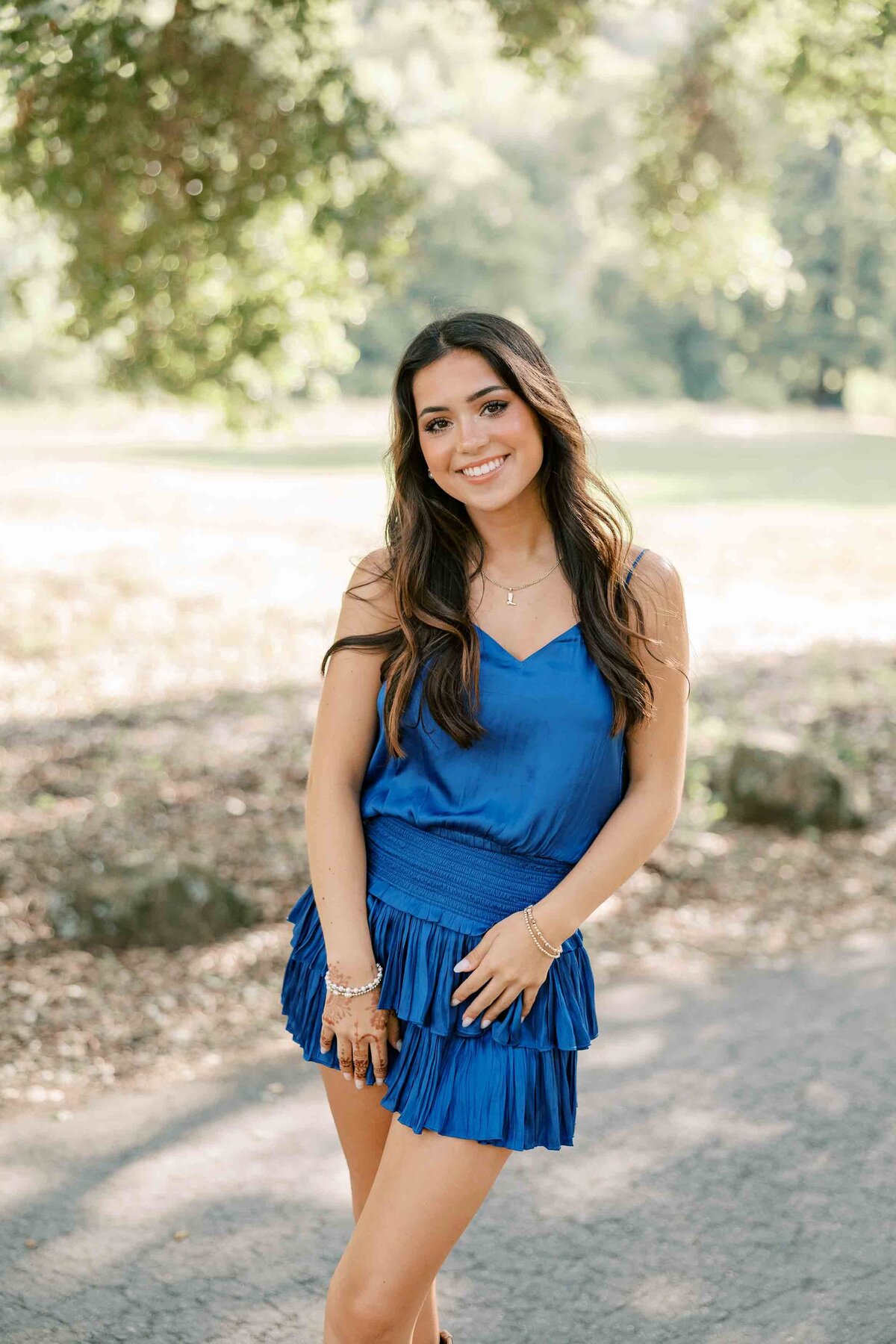 Brunette girl wearing a royal blue dress with her hands on her hips