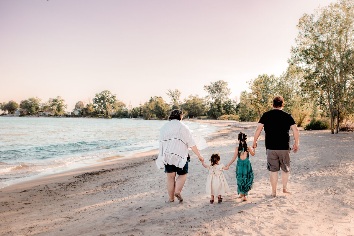 family of four is photographed walking down a beach during sunset