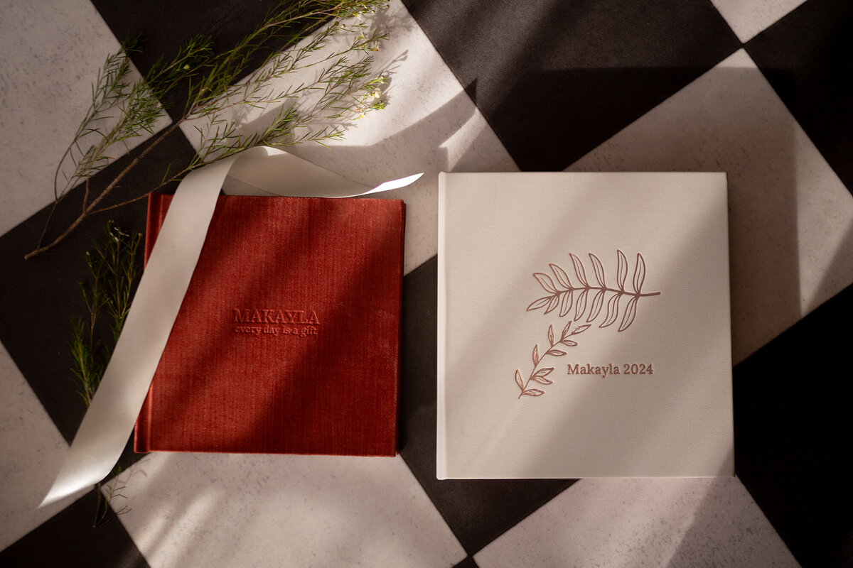 Red and white fine art photo albums lay on a checker tile