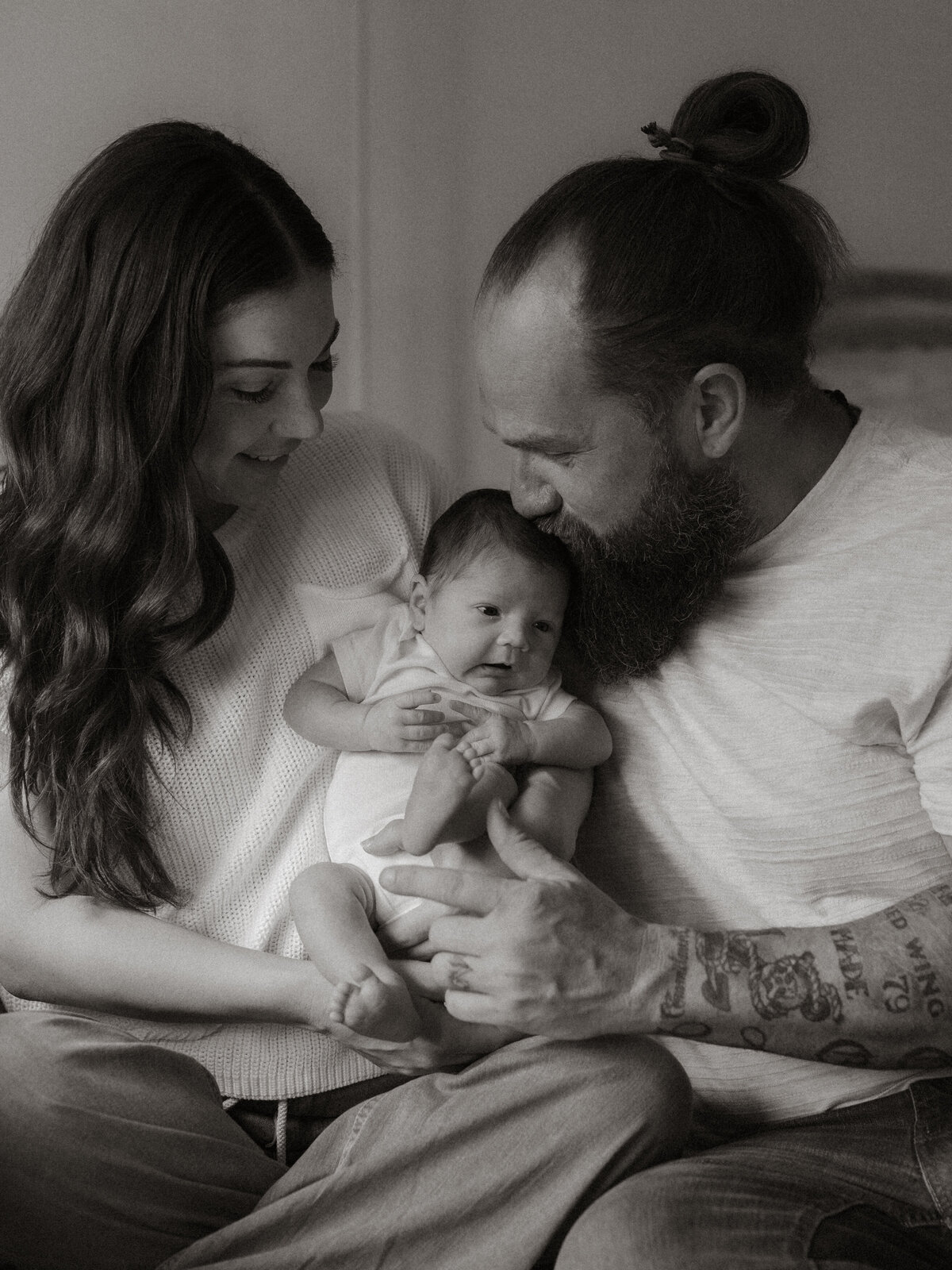 A family cuddles close on the couch, completely absorbed in the miracle of their baby.