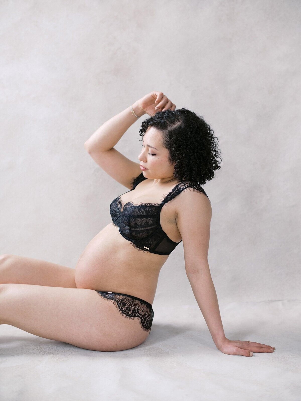 pregnant woman in lace underwear shows off pregnant belly in seattle studio with maternity boudoir photographer Jacqueline Benét 