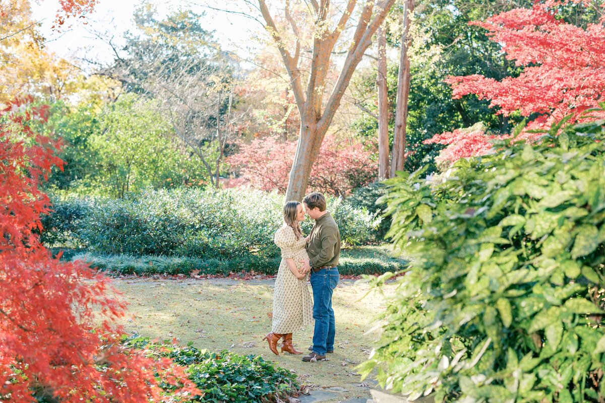 Pregnant woman kisses husband in outdoor garden space