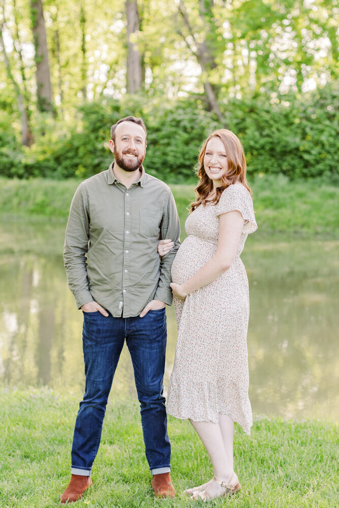 a man and a pregnant woman smiling with arms linked