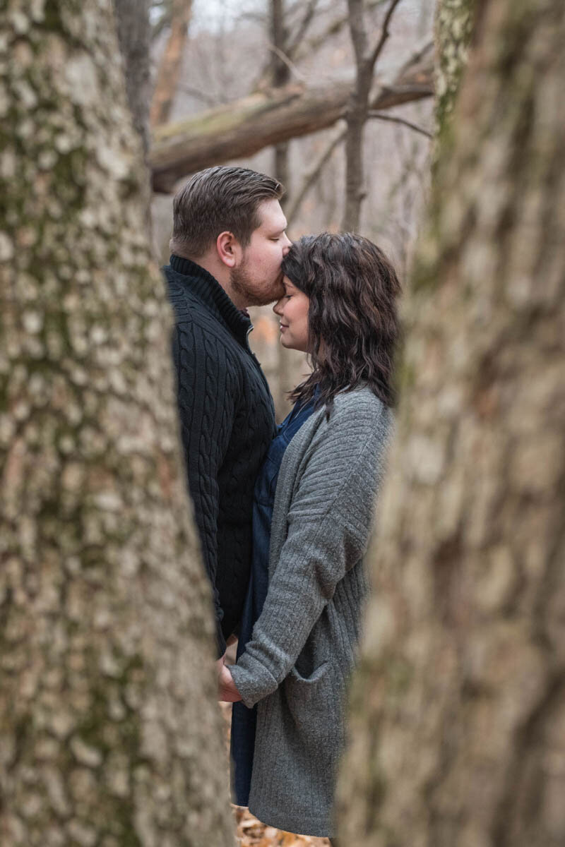 Man kisses woman on her forehead in the forest