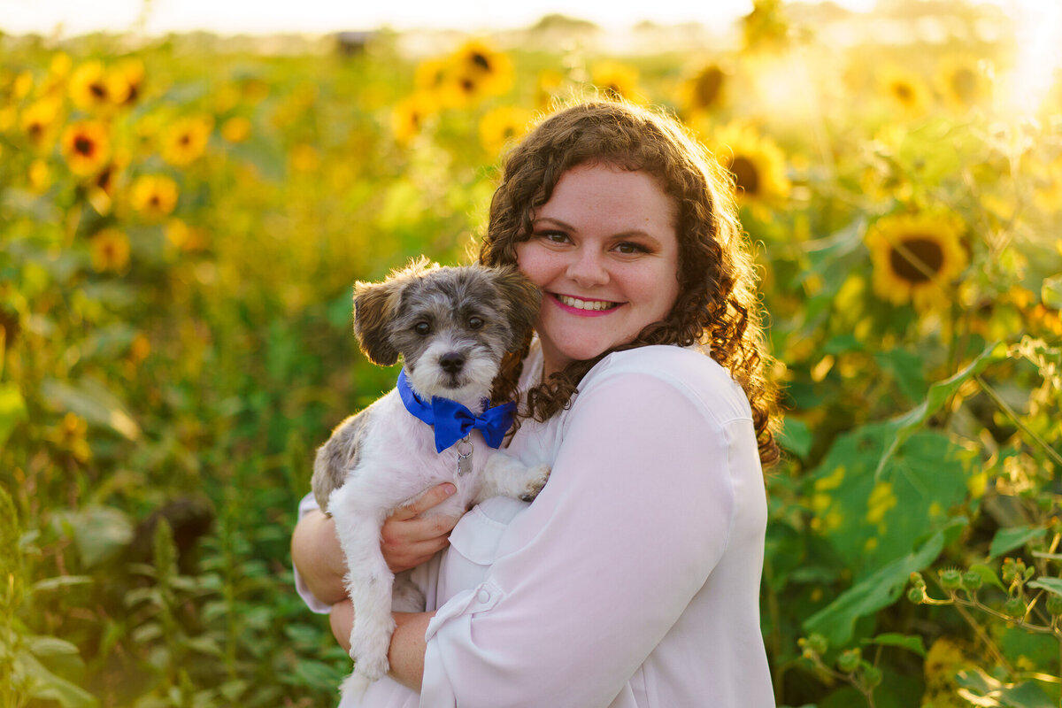 A woman hold her puppy in her arms in a patch of sunflowers - Lynd Fruit Farm Pataskala, Ohio
