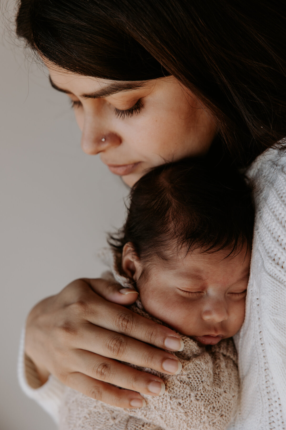 Mother cuddles newborn baby close to her chest