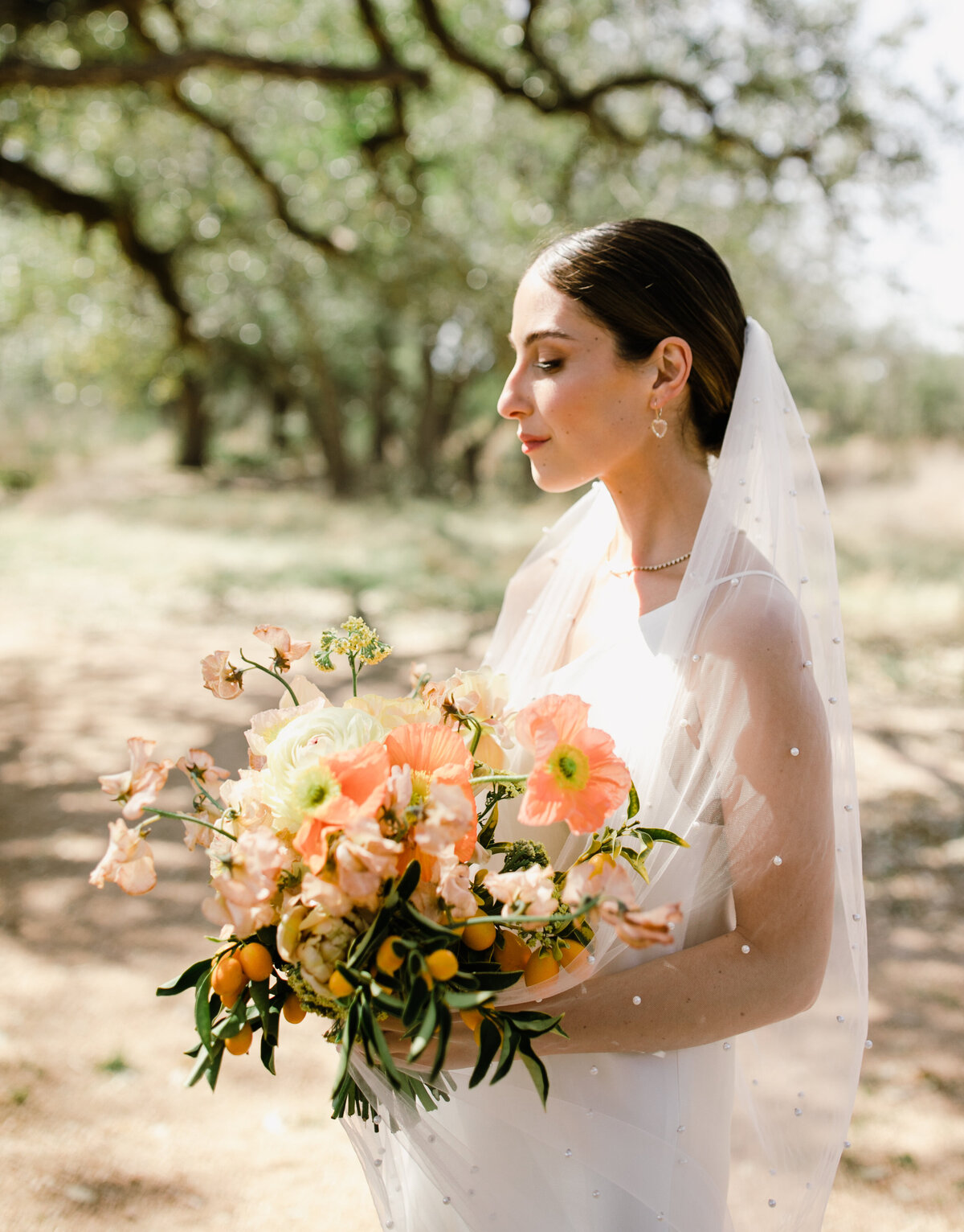Bride holding large bouquet of orange and yellow florals