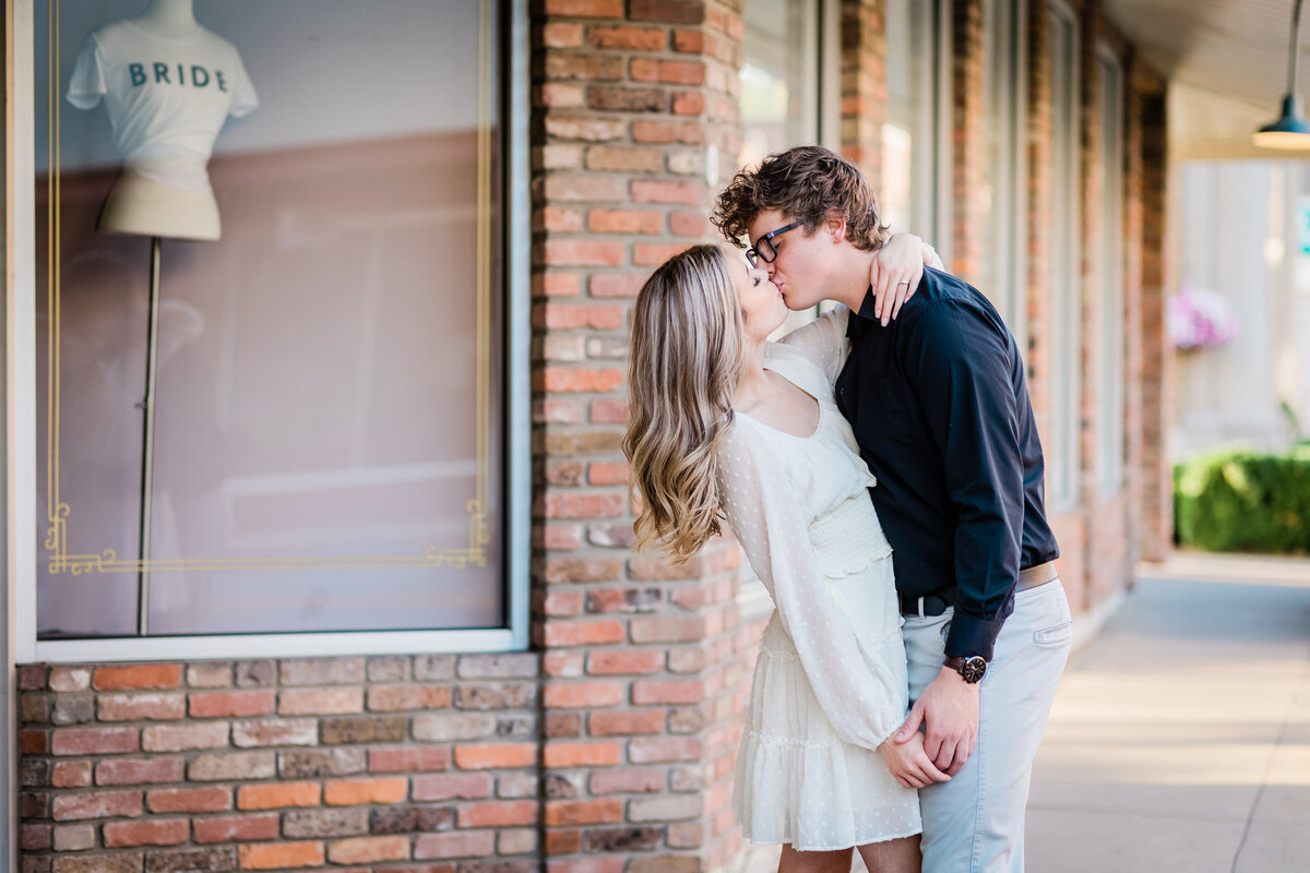 A couple kisses in front of a wedding store in downtown Conway, AR.