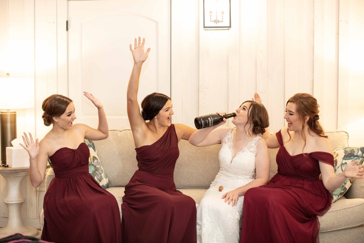bride and bridesmaids in maroon dresses celebrate with champagne at Milestone New Braunfels Texas wedding