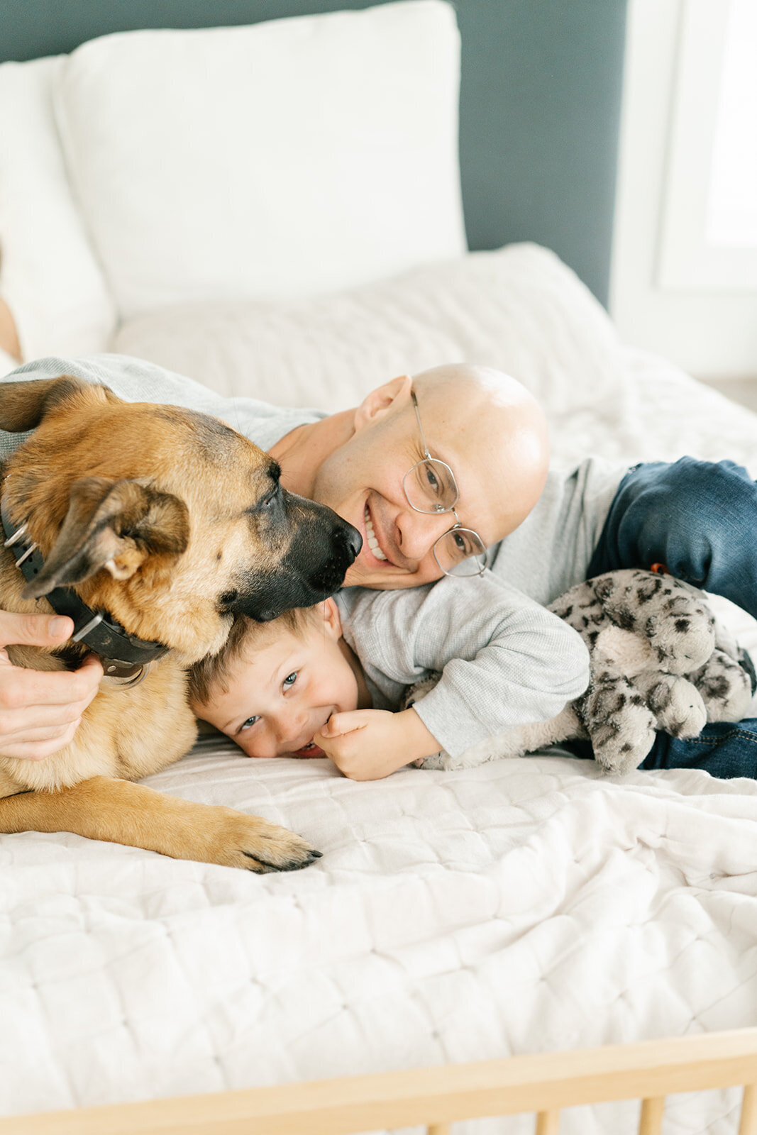 dad, son, and dog snuggled in bed, asheville
