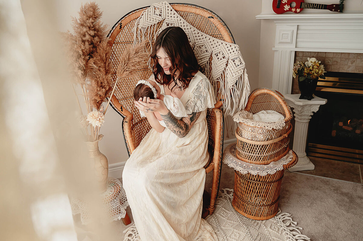 Greater Toronto Photography of mom holding her baby girl at a boho set up on a peacock chair by a window.