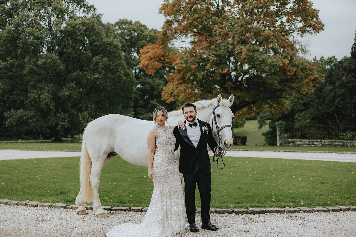 Bride and groom in front of a white horse for their Ireland wedding