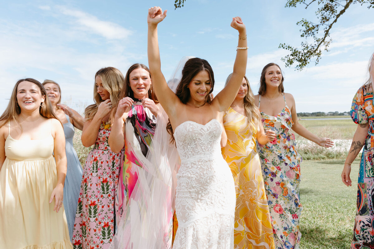 Bride with arms in the air cheering with bridesmaids behind her