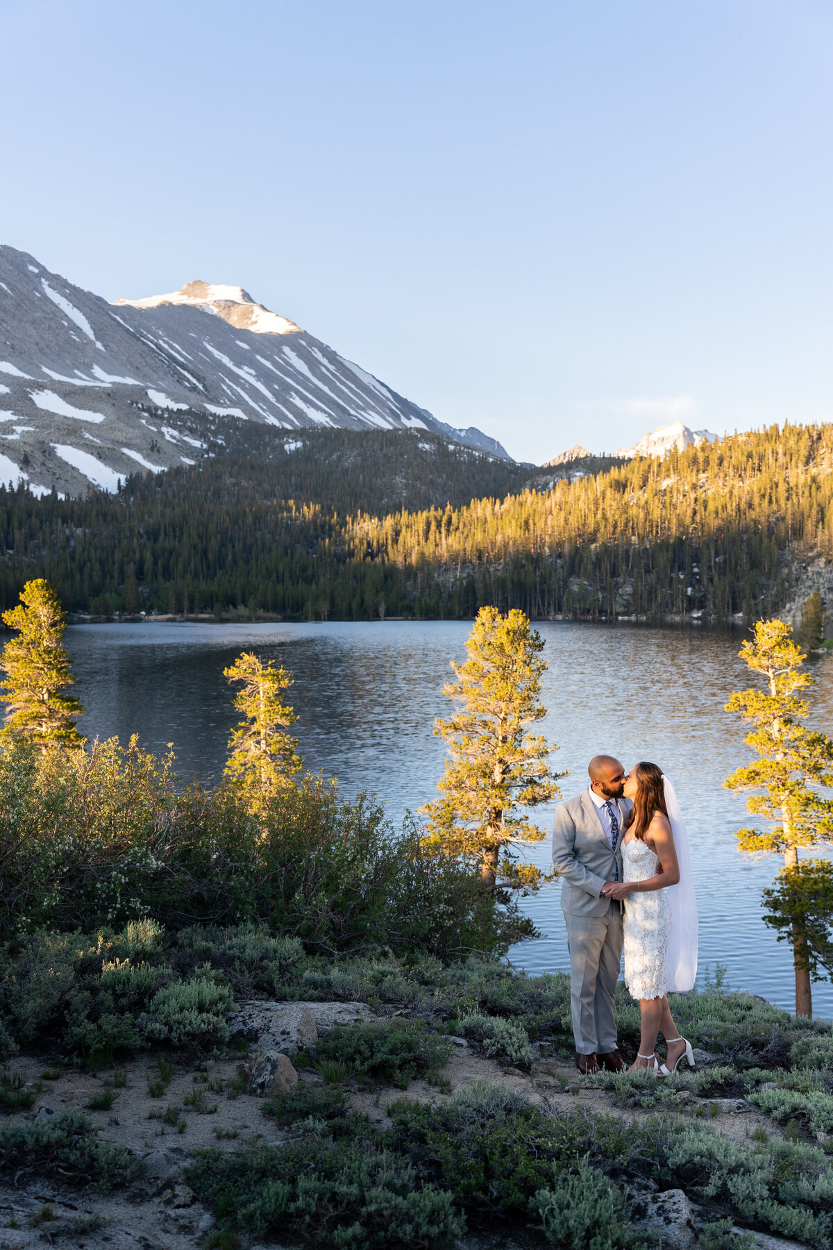 A newlywed couple kissing in front of a lake