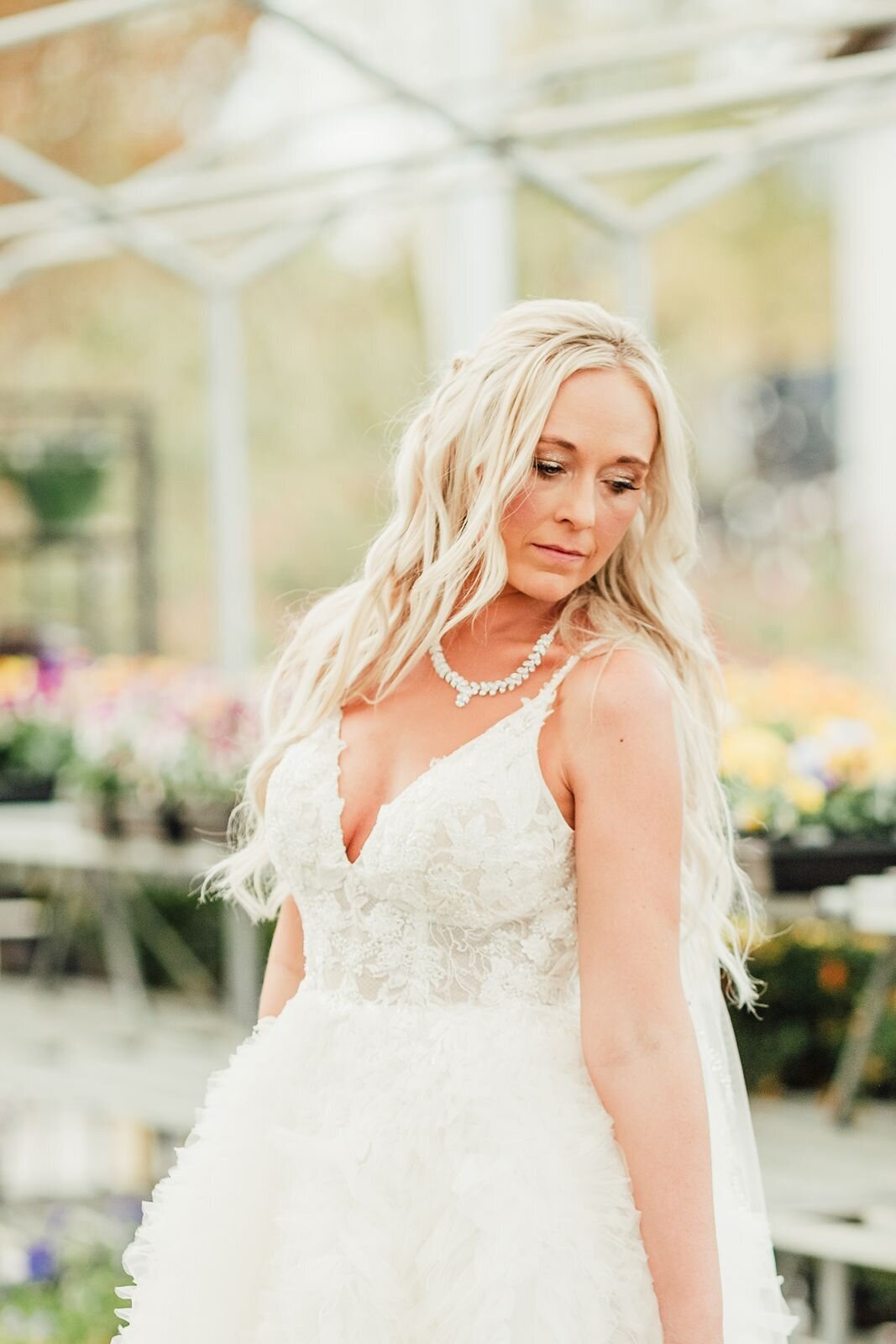 bride poses in wedding attire in a greenhouse nursery