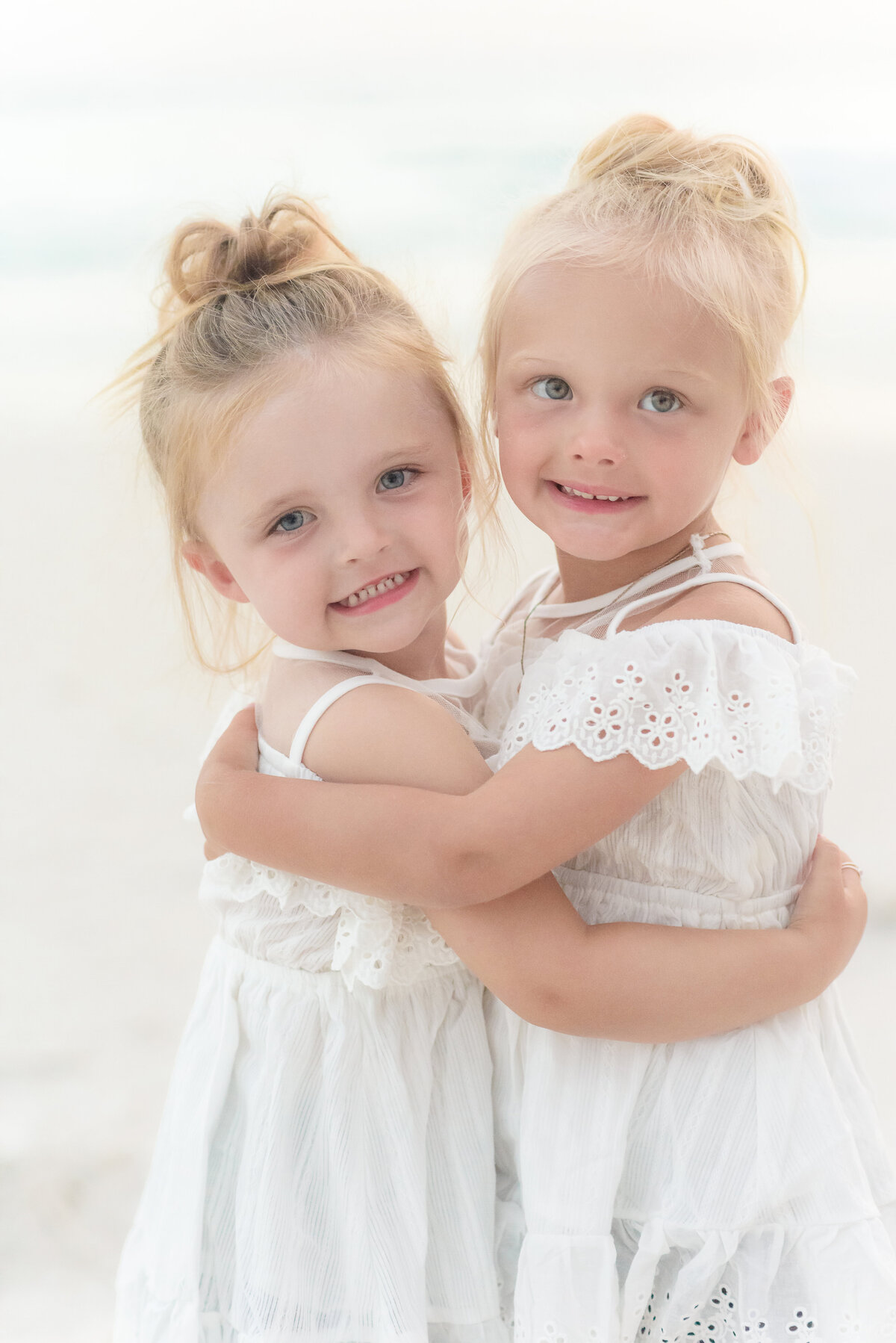 Two toddlers in white dresses at beach family portrait session photo by Michelle Lynn Photography located near Louisville, Kentucky