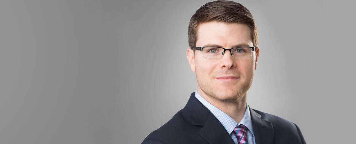 Businessman wearing glasses and a suit against a light gray background