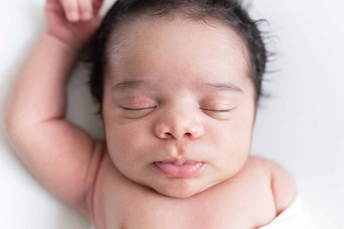 Een gedetailleerde close-up van het gezichtje van je baby. Deze newborn fotoshoot legt de mooiste momenten vast op een natuurlijke manier.