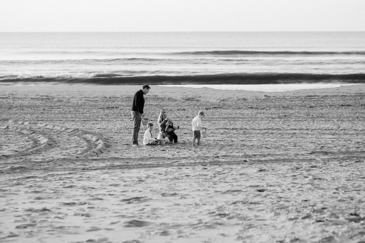 Gezin in de verte op het strand aan het spelen met de zee op de achtergrond