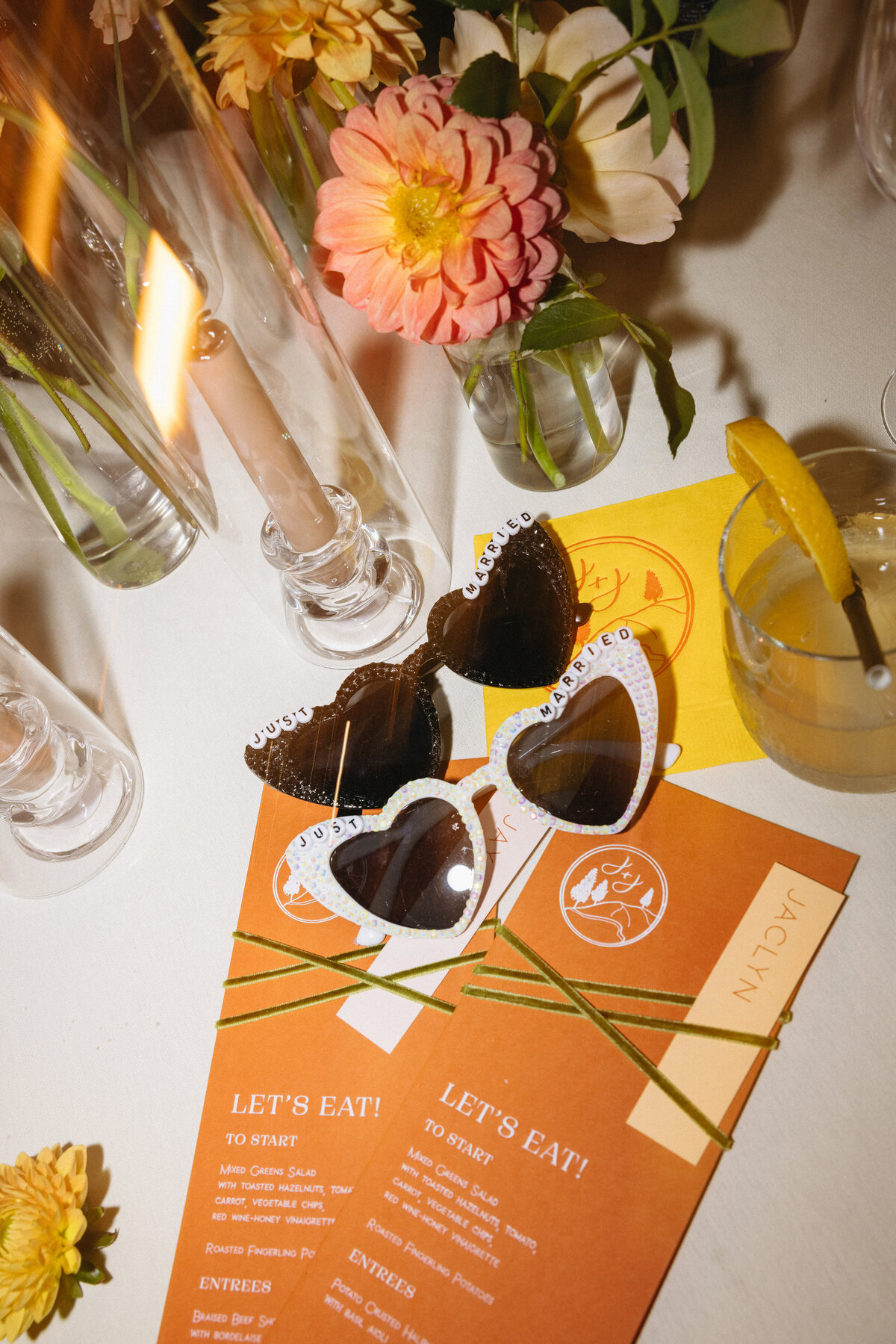 Wedding night flatlay with party sunglasses, flash photography and vibrant dinner menus representing full service calligraphy and design by Life in Letters