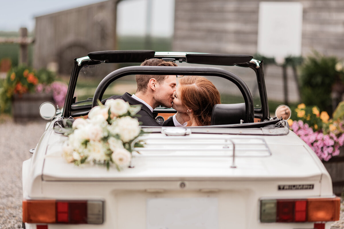 Bride and groom kiss in vintage car
