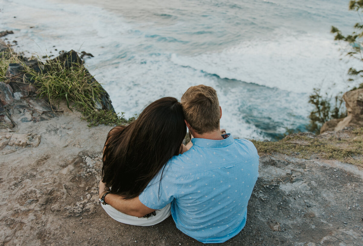 Hawaii Engagement Photographer captures man holding woman at beach watching waves