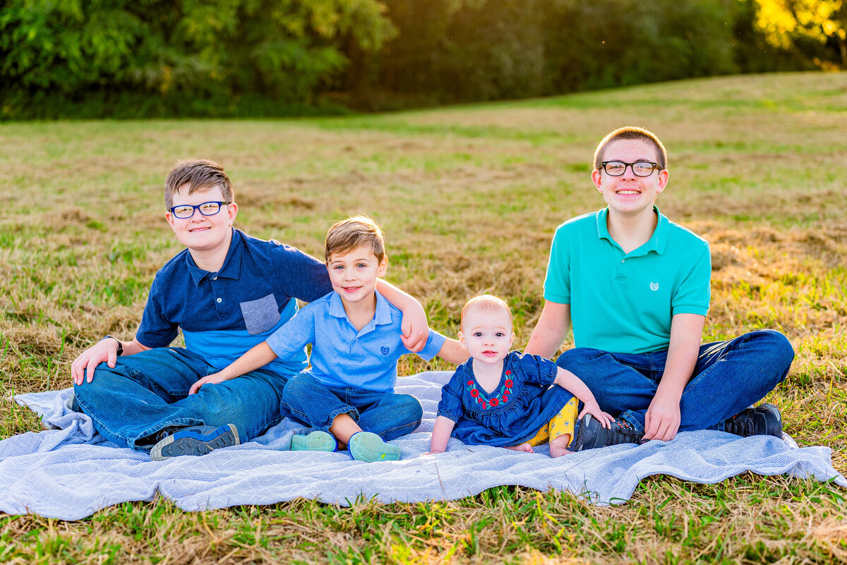 Four siblings pose together on a blanket for family photos at Hayes Nature Preserve in Alabama