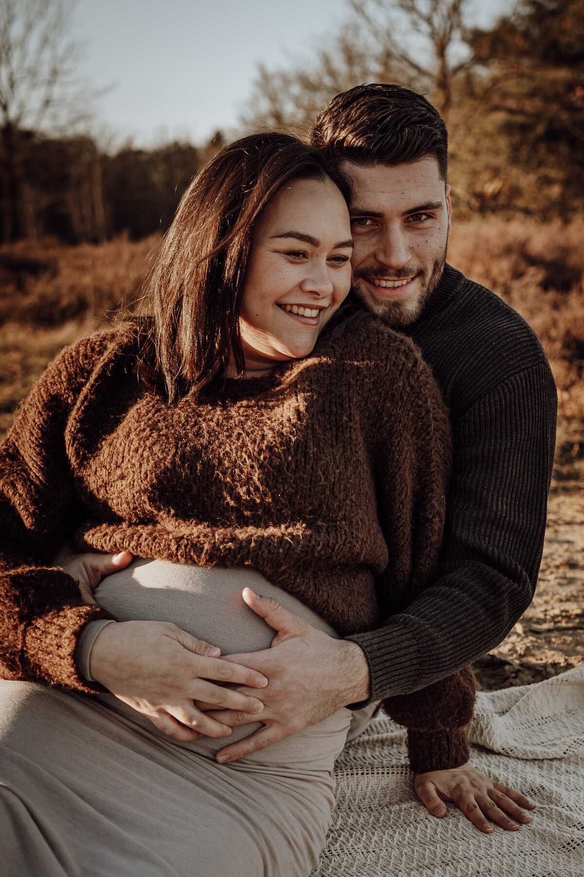 Koppel omhelst elkaar tijdens zwangerschapsshoot op de heide in Antwerpen