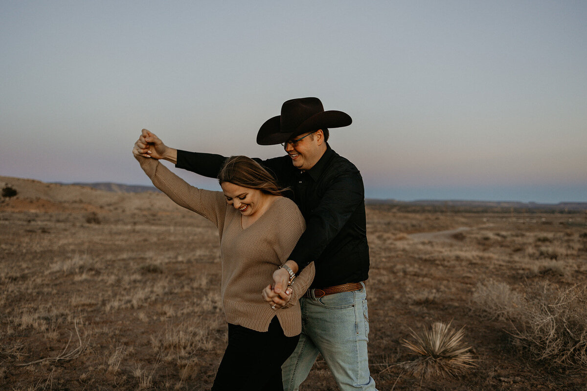 engaged couple walking through the desert laughing