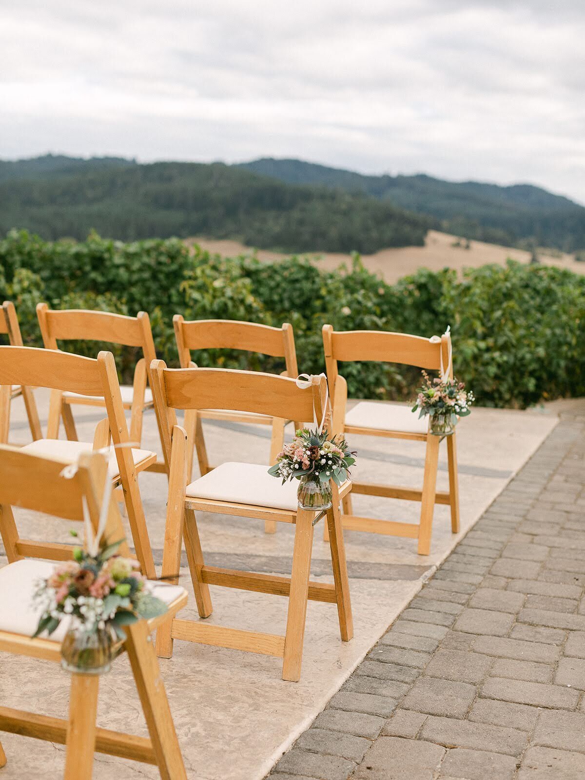 Small floral arrangements hanging from chair at wedding ceremony.