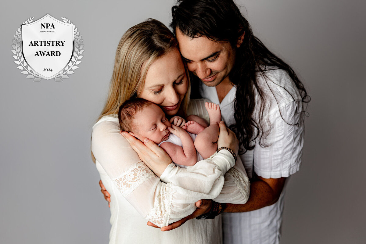 parents cuddling their newborn baby in photo session in studio session in charlevoix